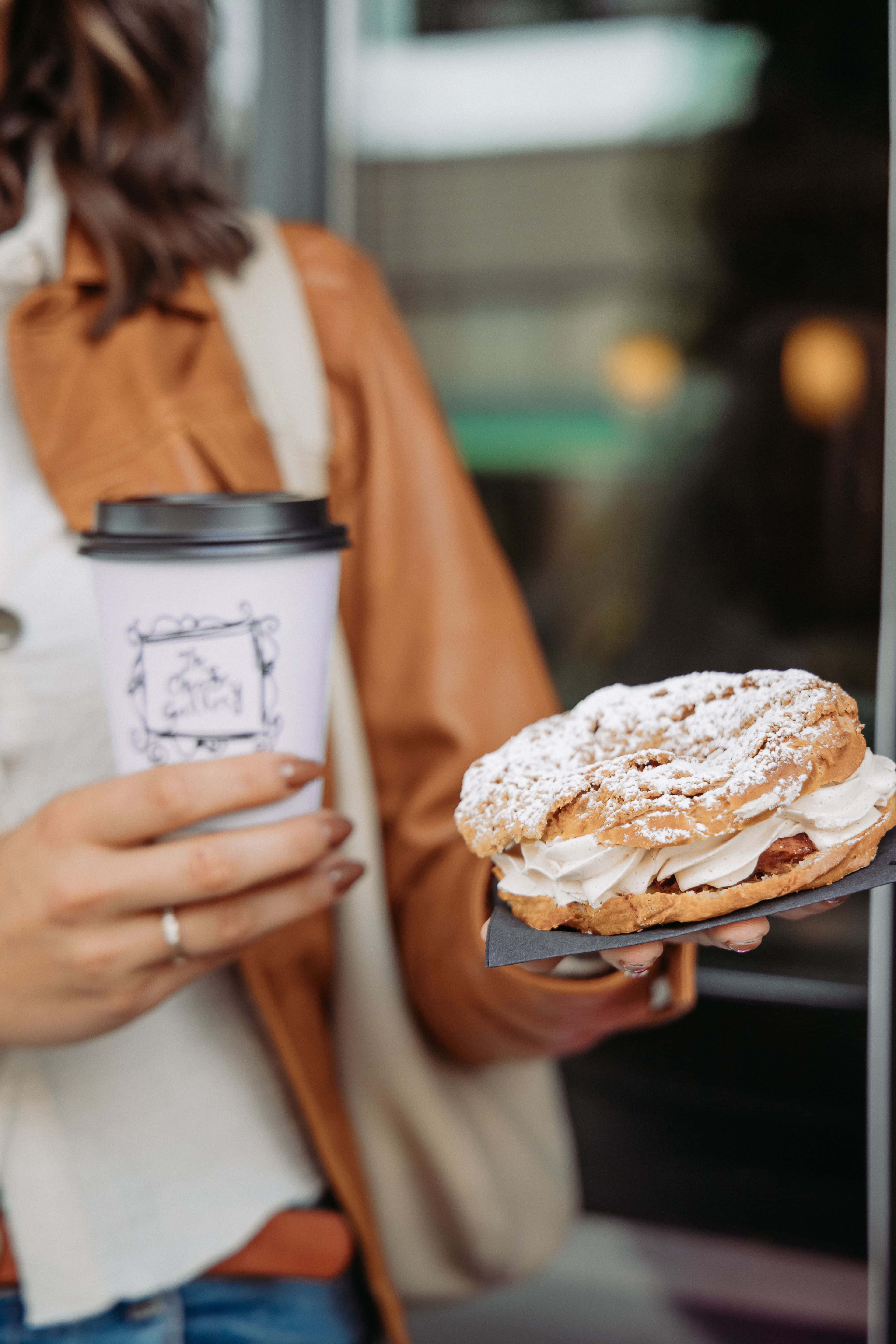 Close up shot of a woman carrying a hot coffee and fresh pastry from The Cheese Gallery in Thornbury