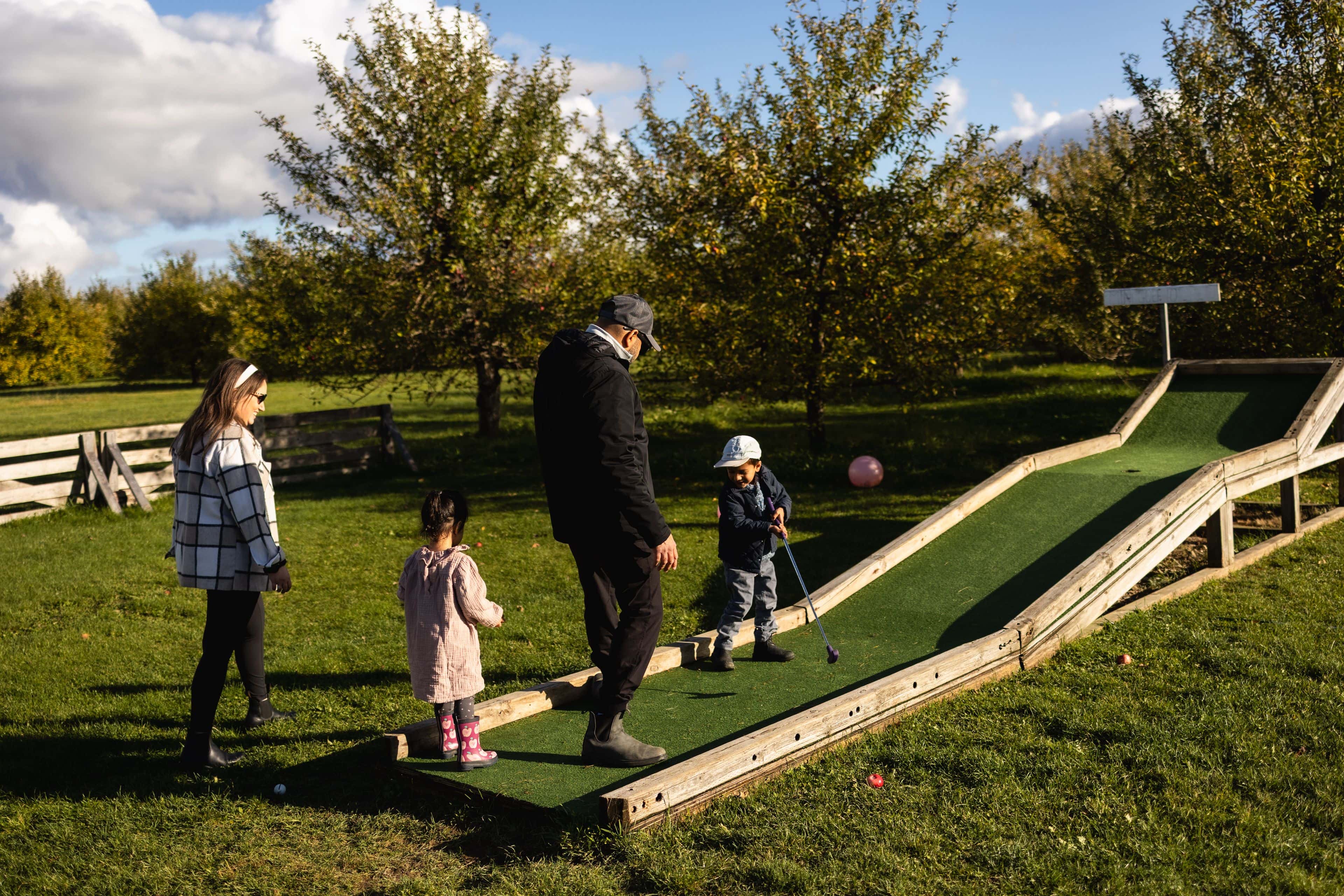 A family of four playing a game of mini putt at the Farmers' Pantry in Clarksburg on a sunny Fall afternoon