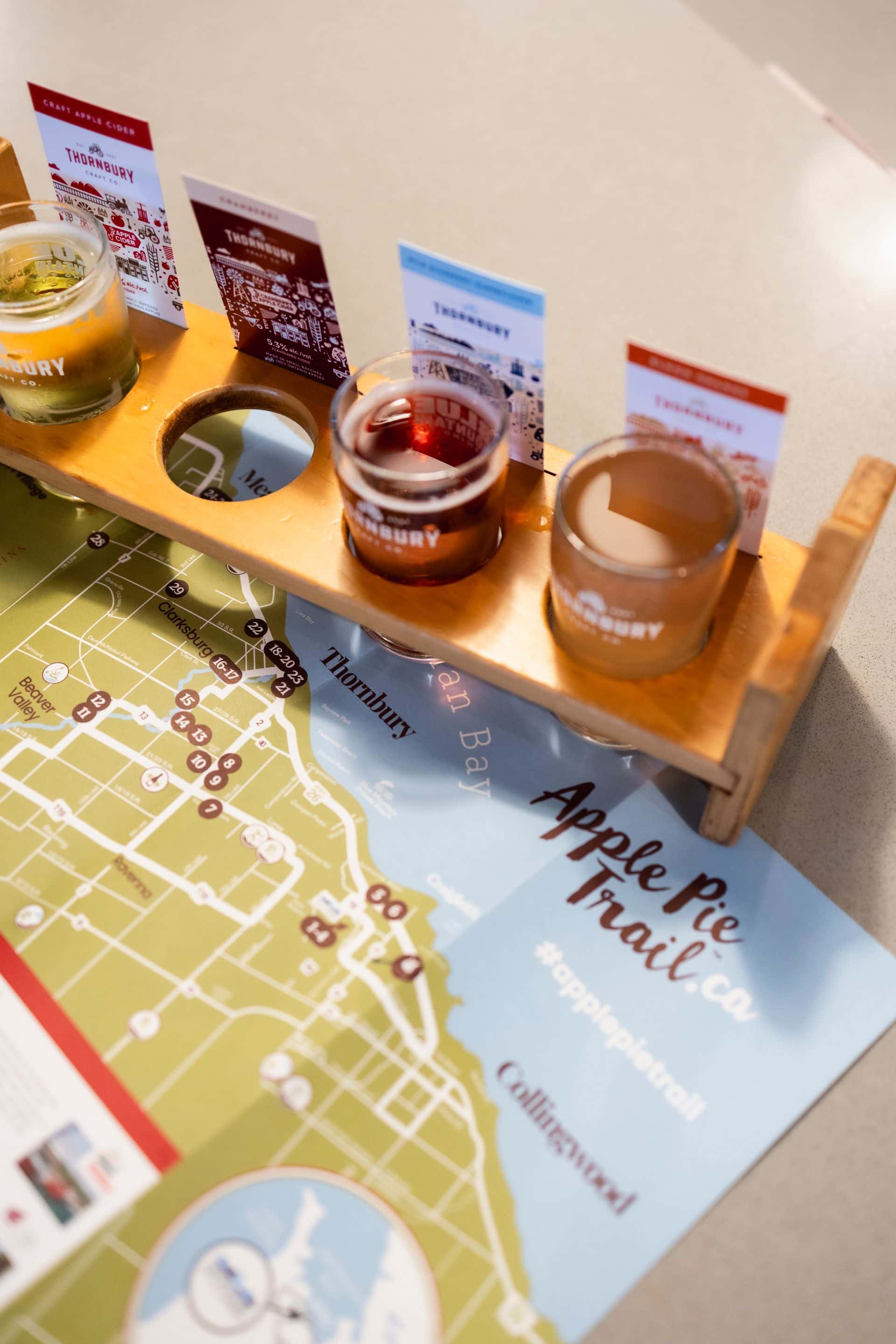 A flight of signature Thornbury Ciders sitting on top of an open Apple Pie Trail brochure showcasing the map of the region