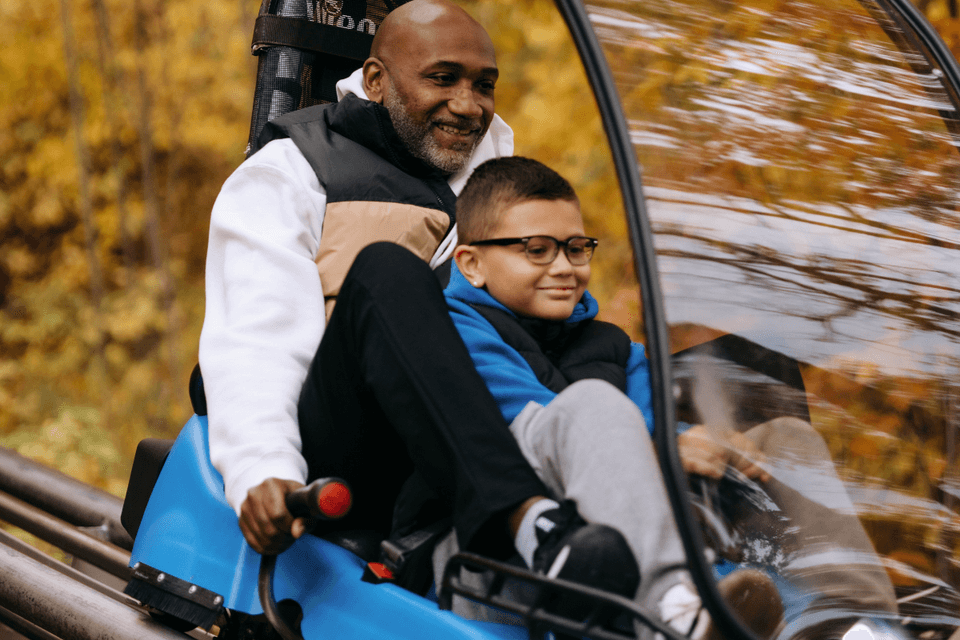 A dad and his son race down through the autumn leaves on the Ridge Runner Mountain Coaster at Blue Mountain Resort