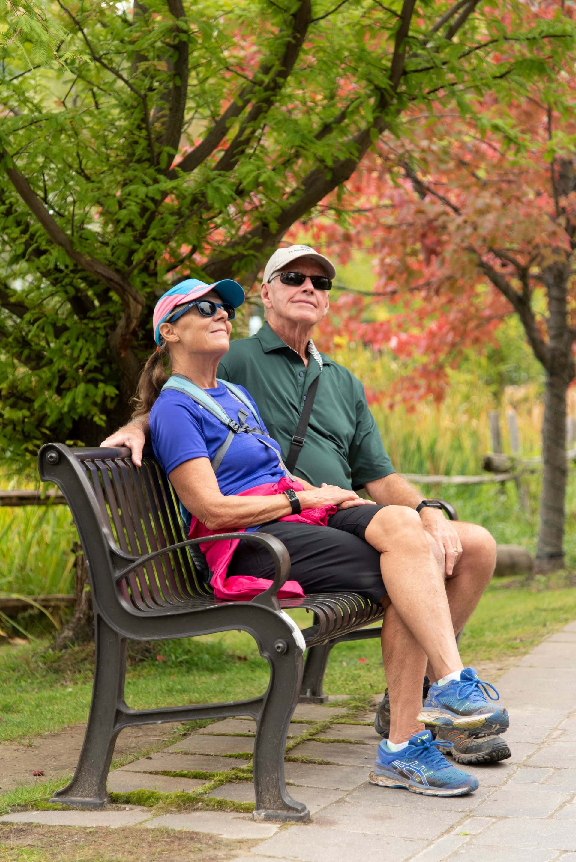A mature couple admiring the fall foliage while taking a break from their stroll on an outdoor bench in Blue Mountain Village