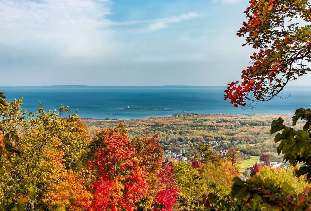 A stunning view of amber and red leaves and South Georgian Bay from the top of Blue Mountain Resort in Fall.