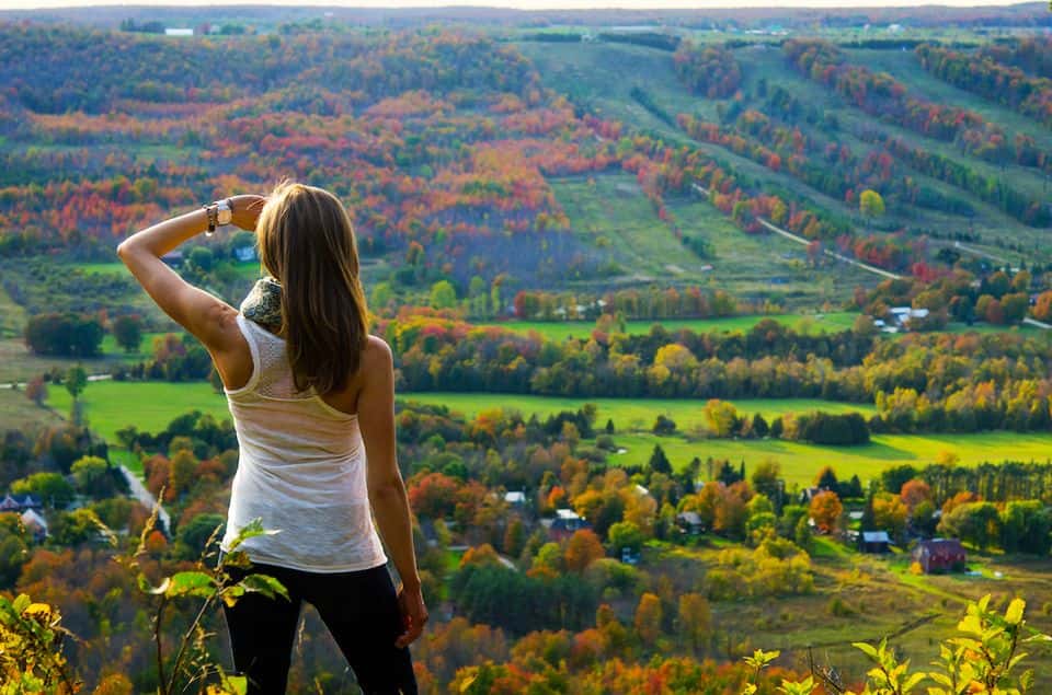A woman gazes out across a stunning view of forests and valleys from the look out point along the Niagara Escarpment