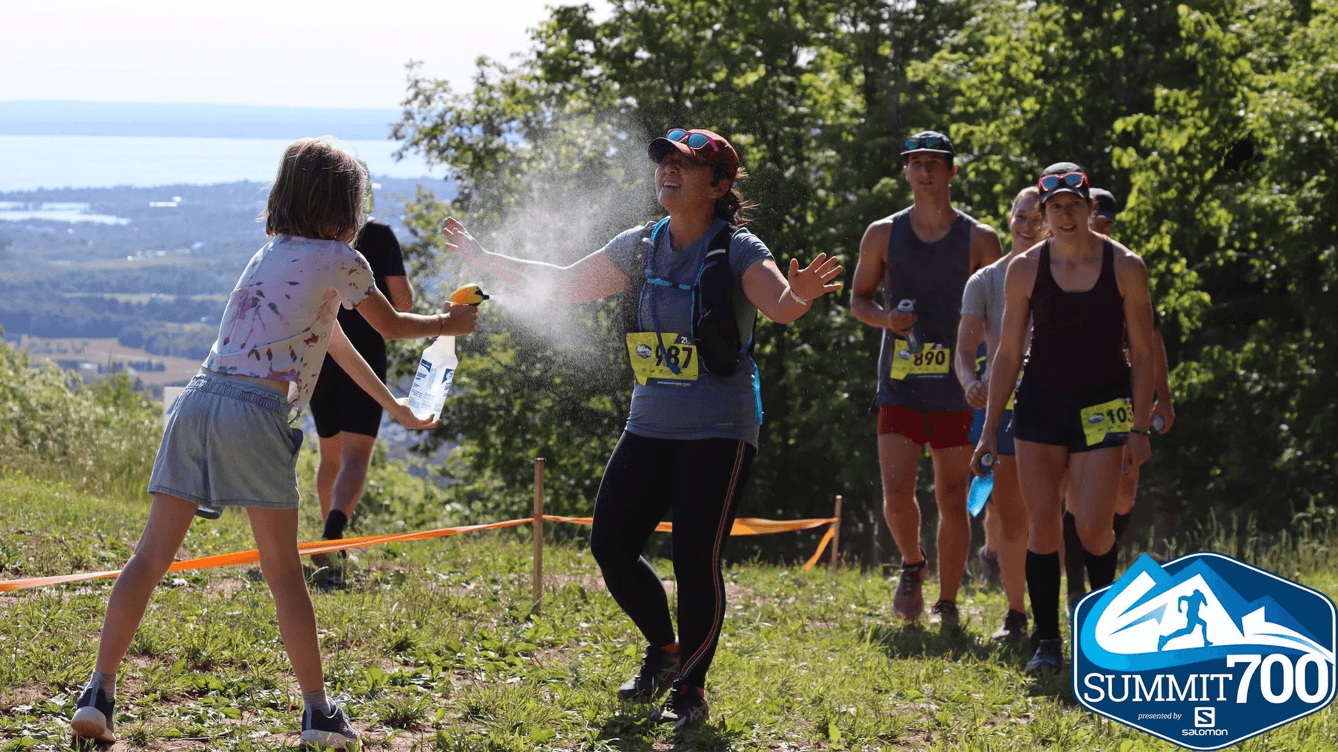 A young volunteer spraying athletes with water as they ascend up the Blue Mountain Trails for Summit 700.