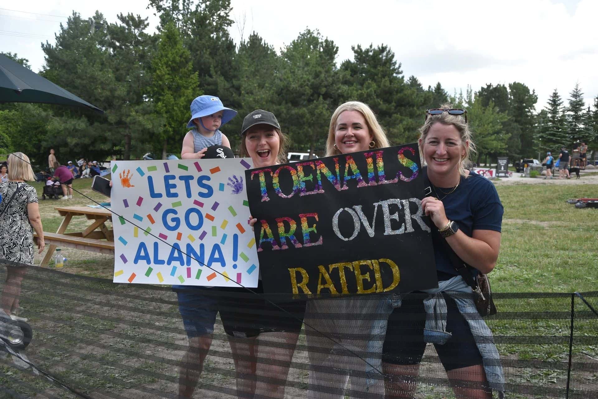 A group of ladies holding up homemade signs to cheer on their racers at Summit 700.