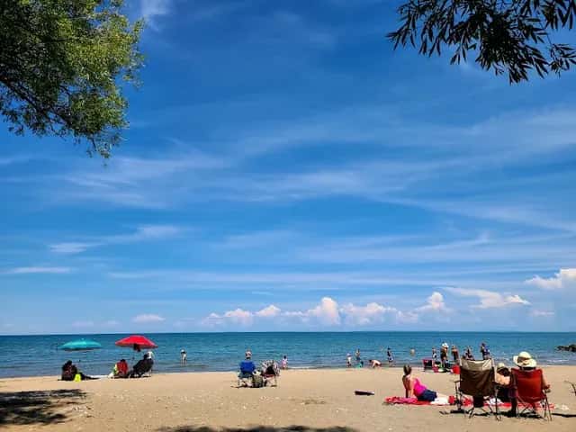 A blue bird day at Northwinds Beach in the Summer, with families and friends sitting in their own groups on the sandy beach.