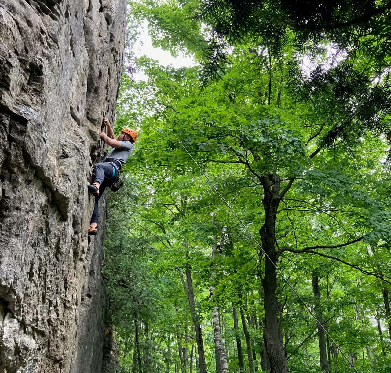 A man climbing up the rock face with On the Rocks climbing adventures in The Blue Mountains.