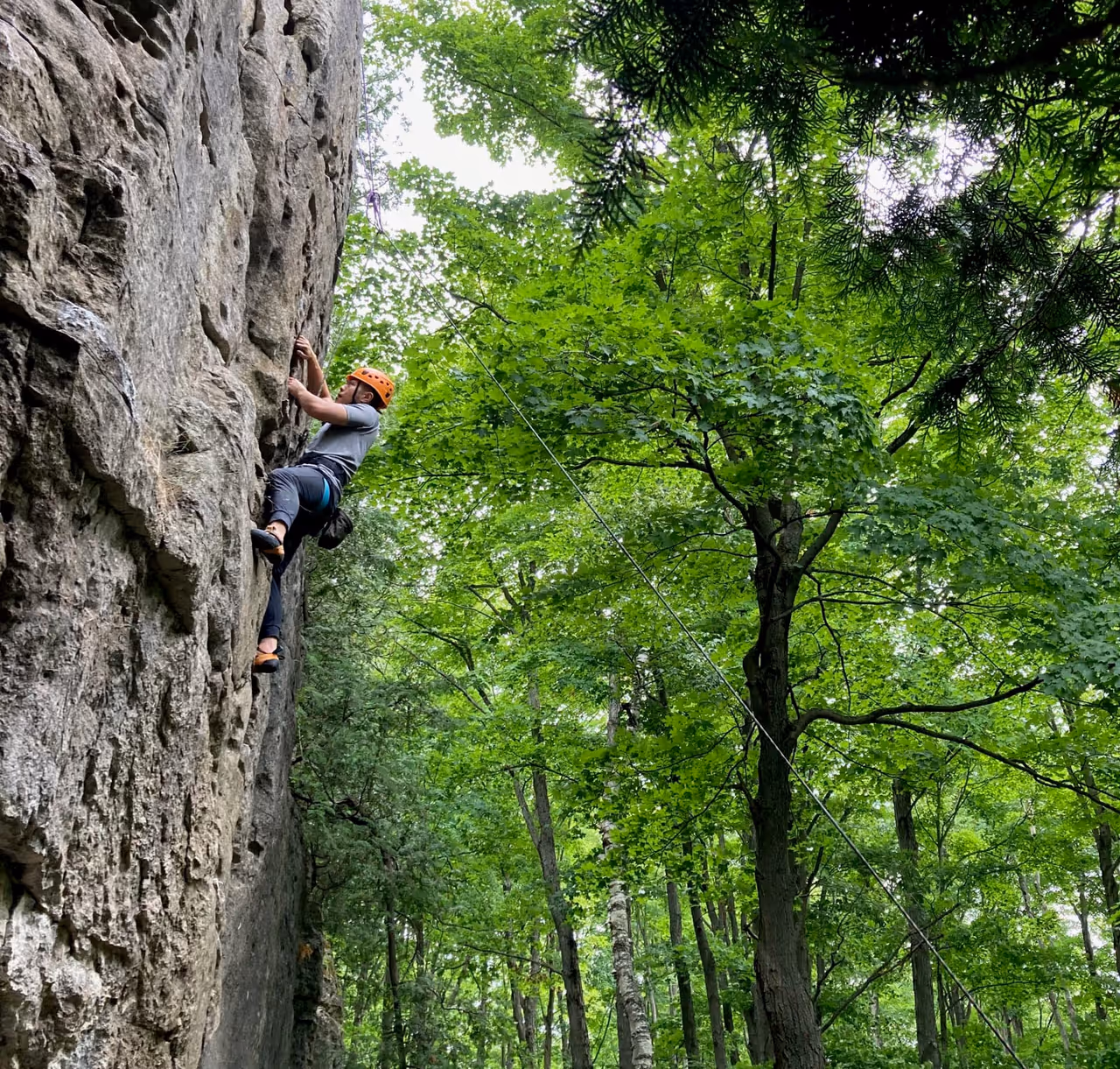 A man climbing up the rock face with On the Rocks climbing adventures in The Blue Mountains.