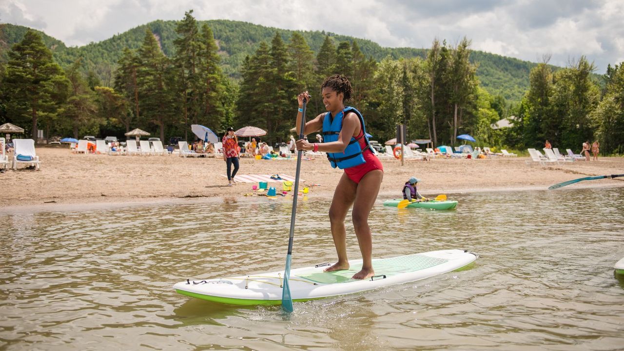 A lady on a stand up paddleboard on Blue Mountain Private Beach. 