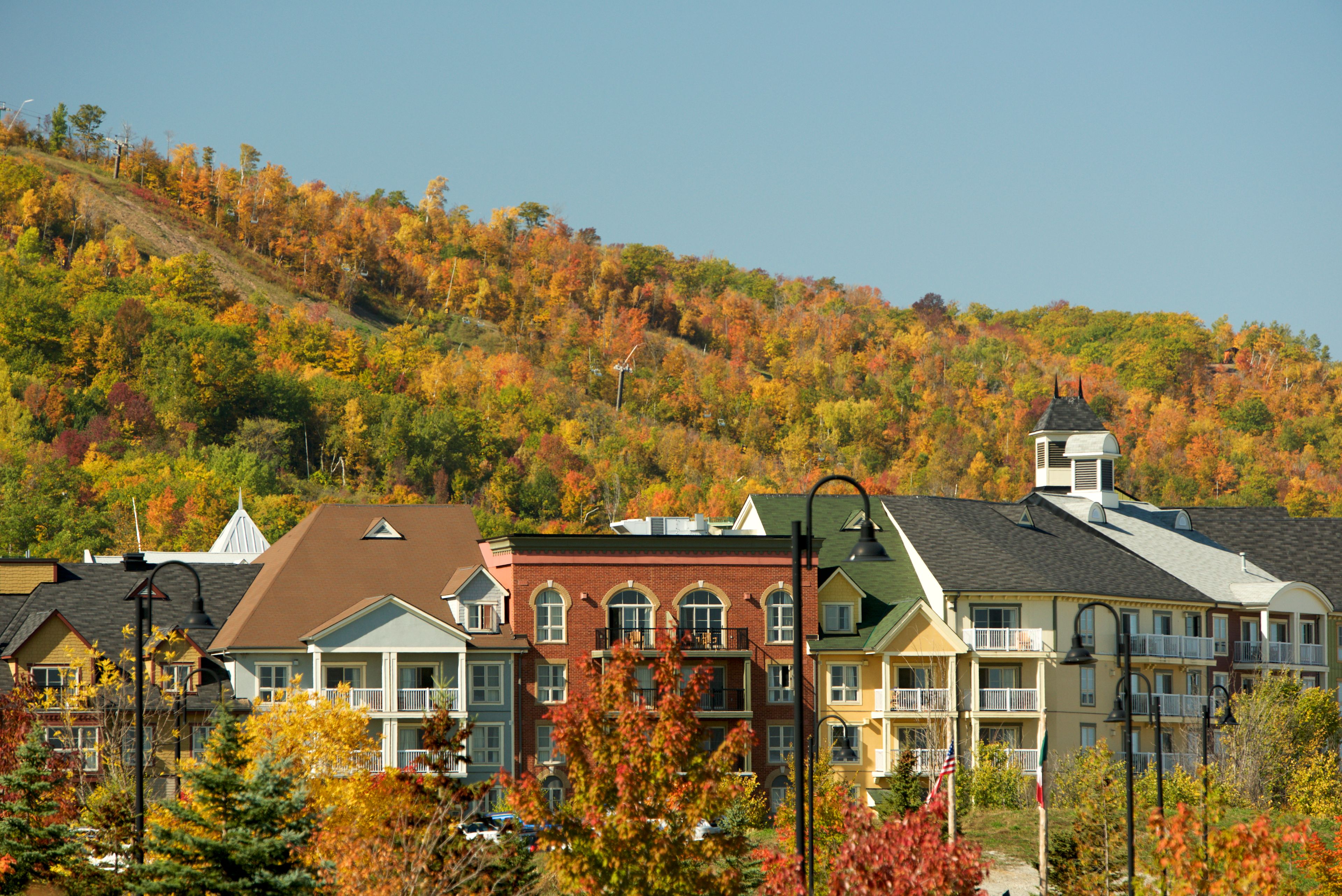 Village Suite Hotels peaking out from the fall foliage with the mountain trails and trees in the background