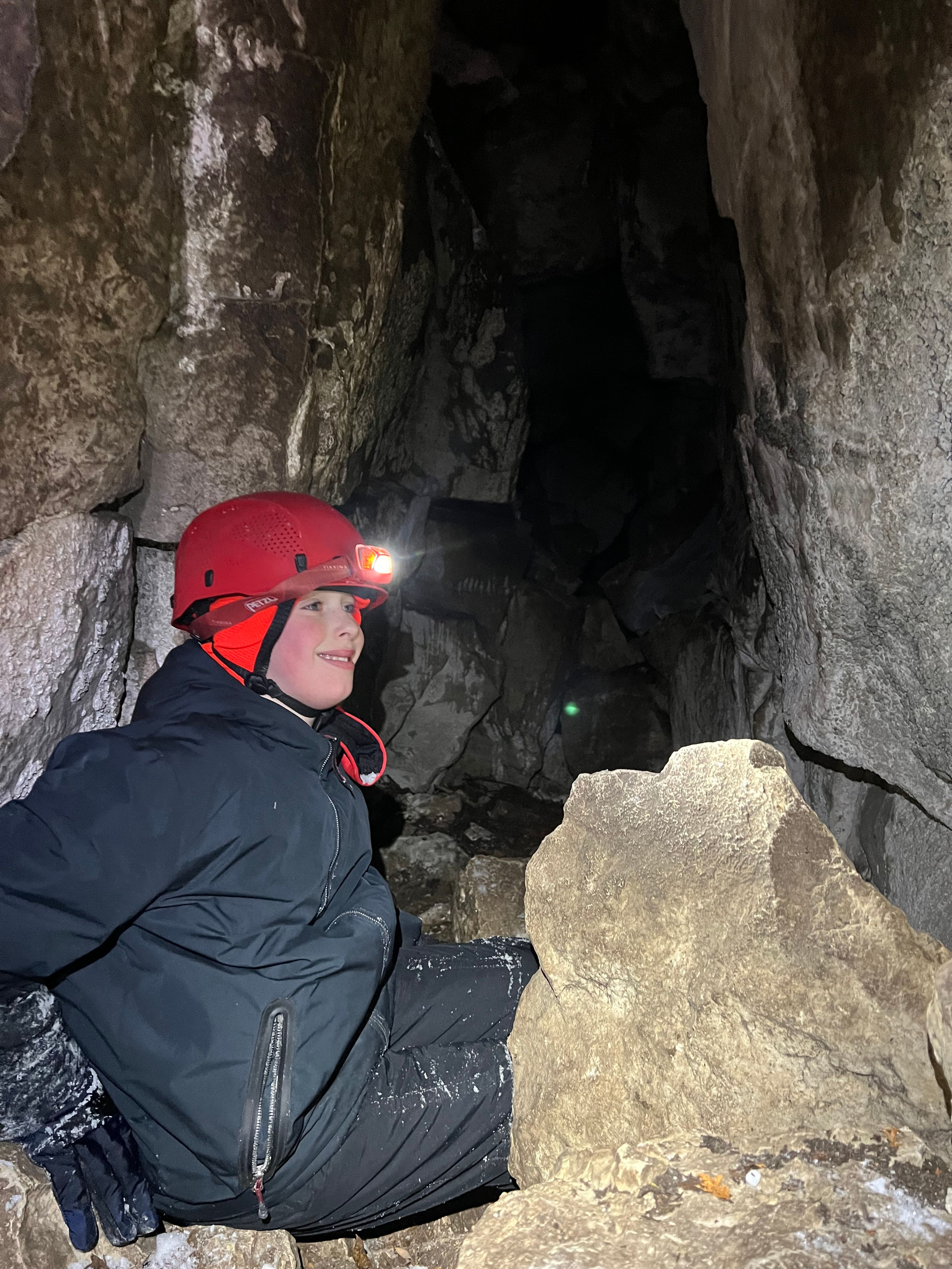 A young boy with a flashlight helmet on his head crawls through the crevices at Scenic Caves Adventures.